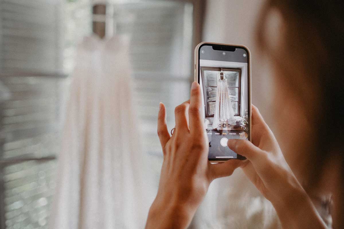 Person macht Foto vom Brautkleid mit Smartphone